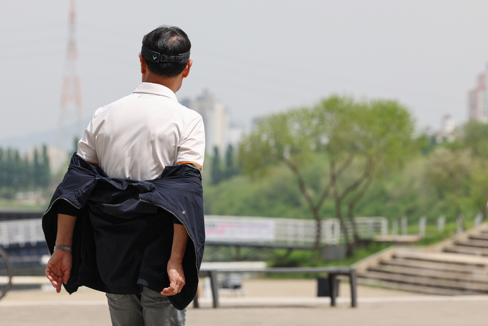 서울 서초구 반포한강공원을 찾은 시민이 긴팔 겉옷을 반만 입고 있다.연합뉴스