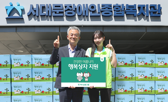 행사에 참석한 하나금융그룹 직원이 송용성 서대문장애인종합복지관장(사진 왼쪽)에게 행복상자를 전달하며 기념촬영을 하고 있다.