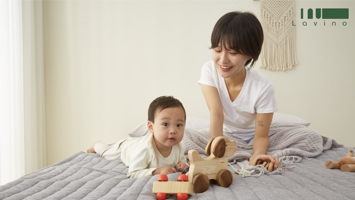 한 아이와 엄마가 라비노 온수매트 위에서 장난감을 가지고 놀고 있다.