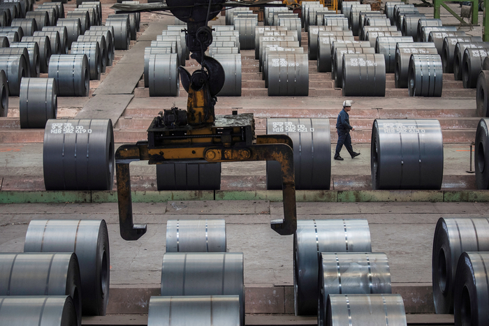 A worker walks past steel rolls at the Chongqing iron and steel plant in Changshou
