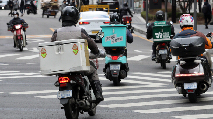 서울시내에서 오토바이 기사들이 음식을 배달하고 있다.