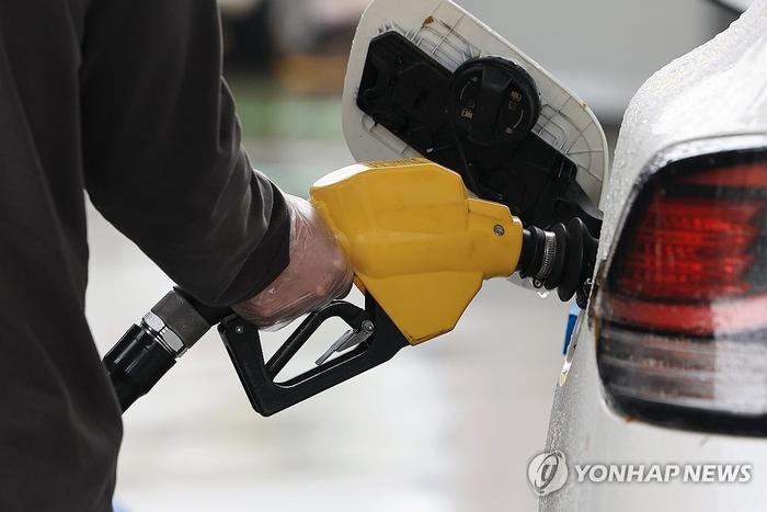 한 운전자가 차에 기름을 넣고 있다.