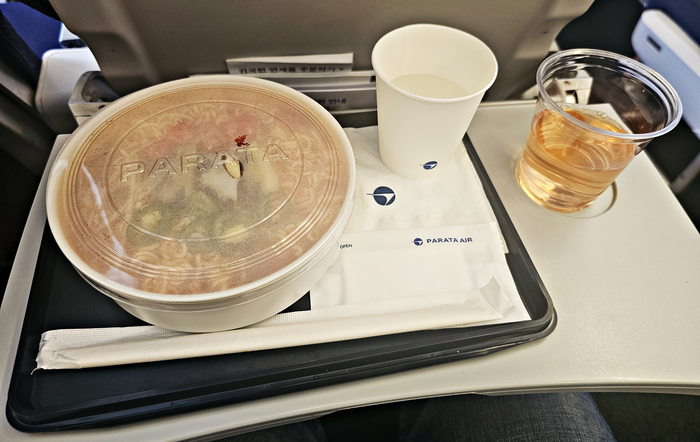 파라타항공 기내 판매 라면이 제공된 모습. 뚜껑이 덮인 종이 대접과 컵에 담긴 물이 트레이에 정갈하게 놓여 있다. 사진=박규빈 기자