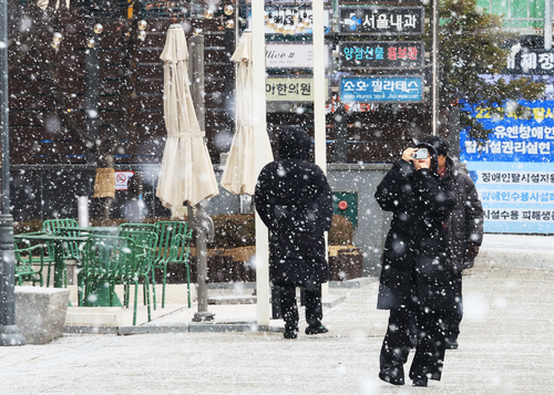 서울 여의도 거리에서 한시민이 내리는 눈을 휴대전화에 사진으로 담고 있다. 2