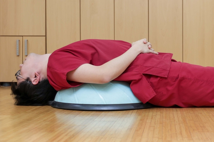 소화불량·복부팽만 개선을 위해서는 넓은 베개나 낮은 짐볼 위에서 뒤로 누워 가슴을 펴고 약 10초 동안 유지한다. 사진=경희대 한방병원