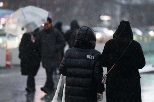 서울 종로구 광화문광장 버스정류장에서 시민들이 외투 모자나 우산을 쓰고 이동하고 있다. 2026.1.12