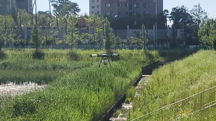 화성시가 인력 접근이 어려운 하천변과 저류지 일대에서 드론을 활용한 방제 작업을 하고 있다. 제공=화성시