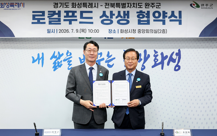 정명근 화성시장(왼쪽)과 유희태 완주군수가 9일 화성시청에서 로컬푸드 활성화 및 도농 상생 협력 업무협약을 체결한 뒤 협약서를 들어 보이고 있다.