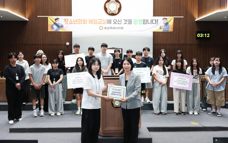 최은희 화성시의회 보건복지위원장이 11일 신청사 본회의장에서 열린 '의회 체험교실'에서 정책제안서를 전달받은 뒤 참여 청소년들과 기념촬영을
