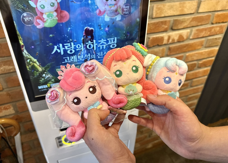 한 고객이 메가MGC커피 매장에서 '캐치 티니핑' 극장판 '사랑의 하츄핑: 고래보석의 전설' 공식 굿즈를 들어 보이고 있다. 사진=메가MGC커피