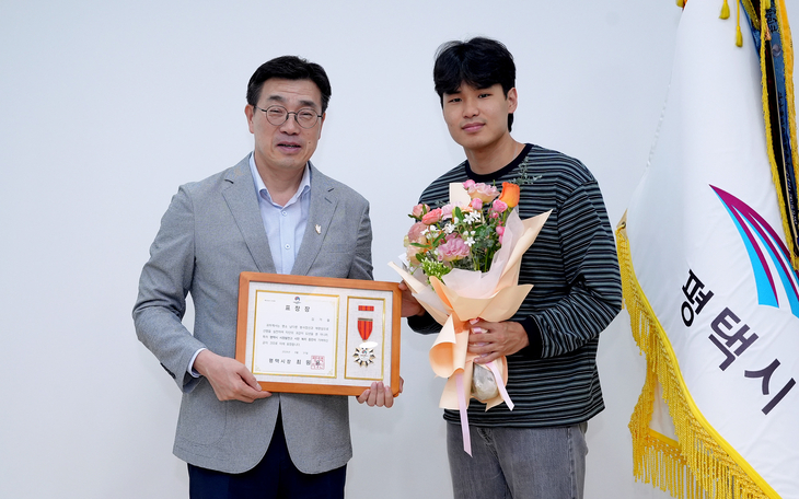 최원용 평택시장(왼쪽)이 교통사고 현장에서 부상자를 도운 고덕동 주민 김가을 씨에게 모범시민 표창장을 수여한 뒤 기념촬영을 하고 있다. 제공=평