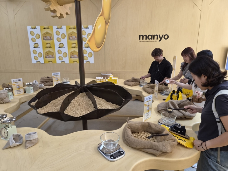 외국인 관광객들이 마녀공장 팝업스토어에서 콩 87g 맞추기 체험을 하고 있다. 사진=여헌우 기자.