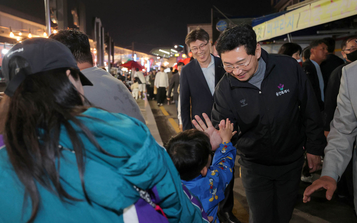 이상일 용인시장이 지난 16일 용인중앙시장 별빛마당 야시장과 김량장 페스티벌 현장을 찾아 어린이와 손을 맞대며 인사를 나누고 있다. 제공=용인시